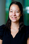 Portrait of Claire Peikes wearing a black dress against a gray and green background
