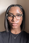 Portrait of Miya Ross wearing a black shirt and glasses