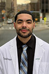 Soloman Jenkins standing outside in an urban setting wearing a white coat and a tie