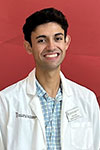 Vijay Modi wearing a white pharmacist coat in front of a red background