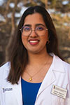 Portrait of Andrea Sequeira standing outside wearing a white coat and glasses